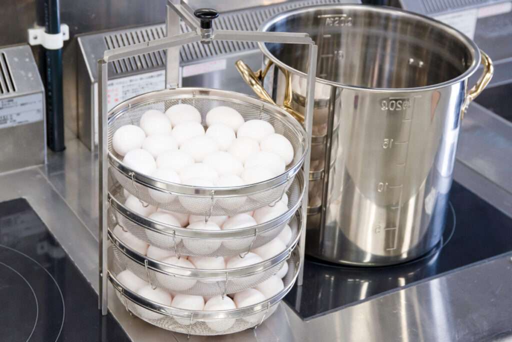 温泉卵を作る鍋とカゴに入っている沢山の白い卵