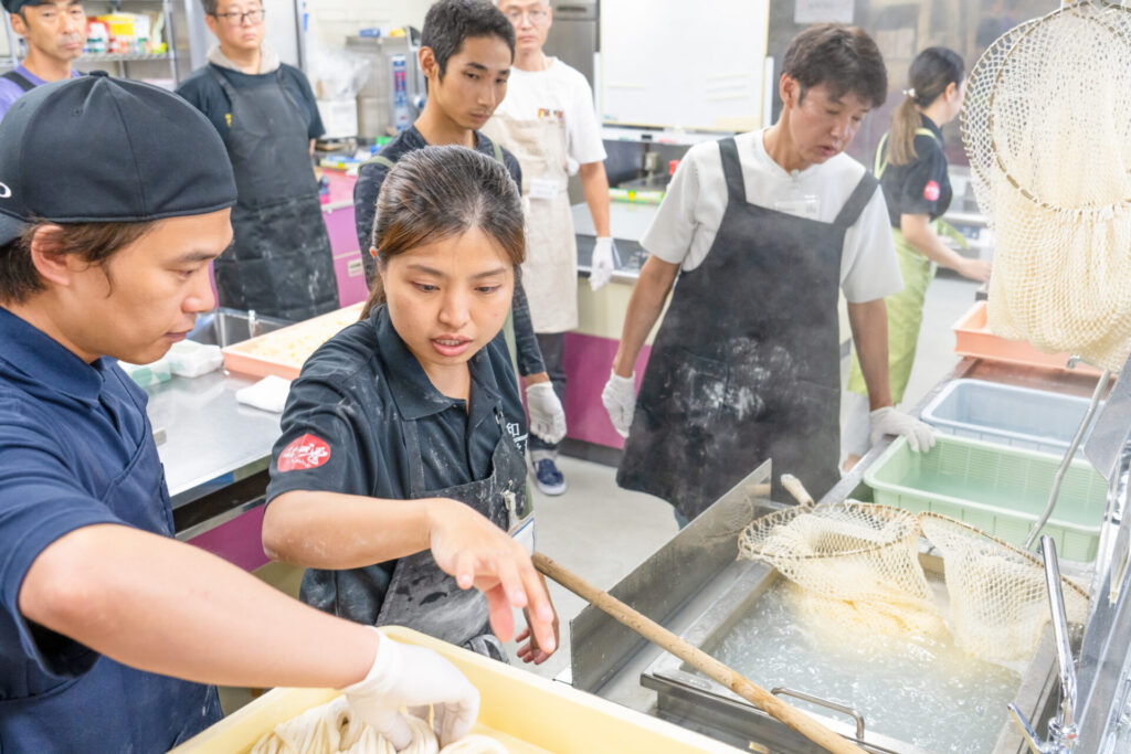 大和うどん学校の生徒さんと講師｜うどんの麺を茹でている
