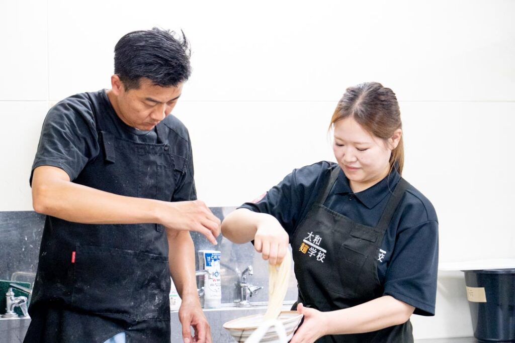 大和うどん学校の生徒さんと講師｜うどんの麺の捻り方のアドバイスを行っている